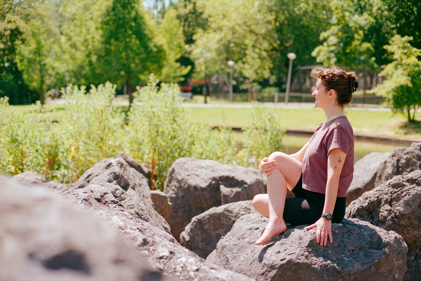 Vero sitting barefoot on rocks in the park, taking a quiet moment